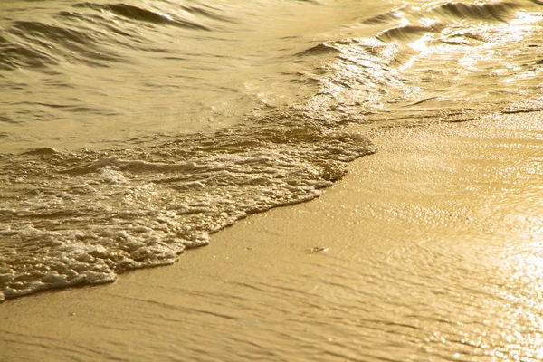 Cerca de olas doradas en la playa de arena al atardecer . —  Fotos de Stock