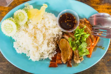 Tayland 'da yüzen bir pazarda ahşap bir masada kızarmış ördek pilavı.