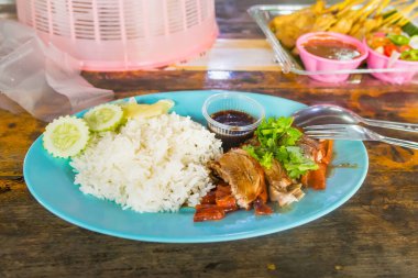 Tayland 'da yüzen bir pazarda ahşap bir masada kızarmış ördek pilavı.
