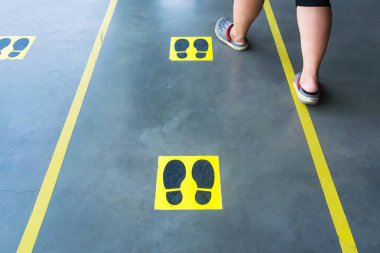 Tayland 'daki süpermarketin zemininde Covid-19' dan Uyarı Ayakizi Sosyal Mesafesi. Kavramsal virüsler tüm dünyaya yayıldı..