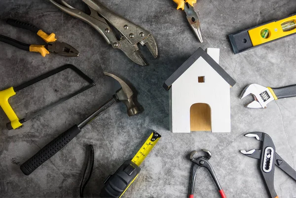 コピースペースとグレー黒セメント床の背景に木製の白い家のおもちゃや建設ツール — ストック写真