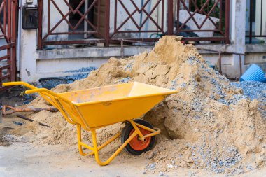 Kumlu el arabası olan bir inşaat alanı.