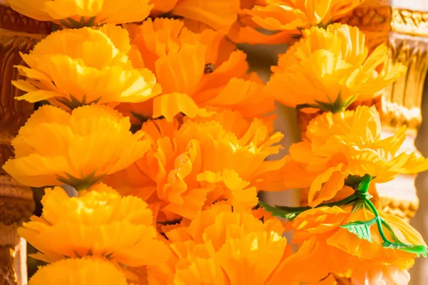 Artificial Marigold flowers used for worship of Buddha, spirit house or holy thing in Thailand. Its yellow color is so bright in the sunny day.