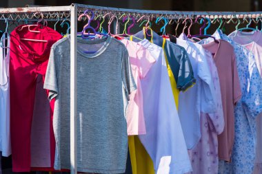 Güneşin sıcağıyla kurumak için çelik çamaşır ipinde asılı renkli ıslak elbiseler.