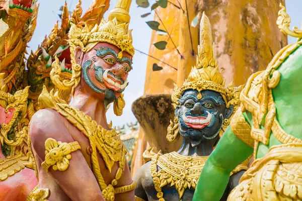 Nakhon Nayok, Thailand - March, 28, 2021 : Golden statue of angel and demons doing tug of war with three-headed serpent, depicting good and evil contest at Maniwong Temple at Nakhon Nayok, Thailand.