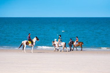 Prachuap Khiri Khan, Tayland - Nisan, 03, 2021 Hua Hin, Tayland 'da sıcak güneş altında Hua hin plajında at süren insanların isimleri..