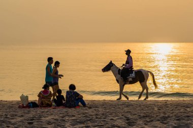 Prahuap Khiri Khan, Tayland - Nisan 04, 2021: Tanımlanamayan insanlar, sabahın ilk ışıklarıyla Huahin 'in Prachuap Khiri Khan, Tayland sahilinde deniz dalgalarıyla bir ata biniyorlar.
