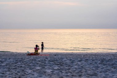 Prachuap Khiri Khan, Thailand- April, 03, 2021 : family enjoys their time on the beach in the morning sunrise of Thailand.