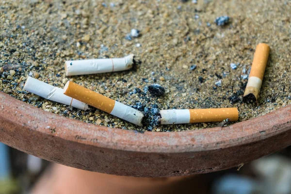 Sigara izmaritleri ve küllerle dolu yanmış sigara çöpü..