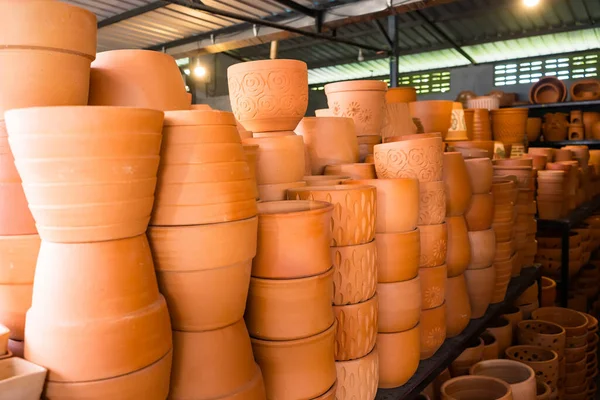 Metal bir çatı altında, kapalı bir çömlekçide çeşitli şekil ve boyutlarda terakotta kil kaplar sergileniyor.
