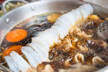 Karides, sebze ve et ile dolu sıcak bir tencere yakın plan bir Asya restoranında, arka planda lokantalar ve et kaynıyor.