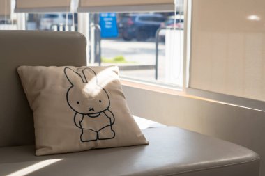 Dekoratif yastıklarla aydınlık güneşli bir alan modern beyaz bir kanepede büyük bir pencerenin yanında rahat bir oturma yerinde.