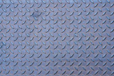 Endüstriyel zemin ve güvenlik uygulamalarında kullanılan yükseltilmiş lastik desenli metalik elmas plaka yüzeyine yakın plan.