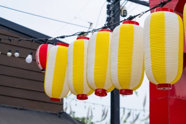 Sarı ve beyaz Japon kağıt fenerlerinin oluşturduğu sıra açık şehir sokak ortamında asılı duruyor.