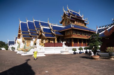 Chiang Mai, Tayland - Ocak, 06, 2026: Canlı mavi çatıları ve karmaşık mimari detayları ile huzurlu tapınak, kültürel miras ve ruhani bağlılığın bir kanıtı olarak duruyor. Tapınağın yakınında bir keşiş yürüyor..