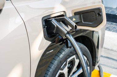 Chiang Mai, Tayland - Ocak, 08, 2026: Elektrikli Otomobil Şarjı: Bir elektrikli arabanın şarj portunun aktif olarak bağlanması, modern ulaşım, temiz enerji ve çevresel bilinci sembolize etmesi,.