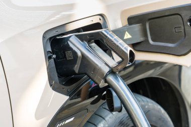 Chiang Mai, Tayland - Ocak, 08, 2026: Elektrikli Otomobil Şarjı: Bir elektrikli arabanın şarj portunun aktif olarak bağlanması, modern ulaşım, temiz enerji ve çevresel bilinci sembolize etmesi,.