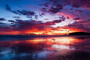 Renkli gökyüzü gün batımında sahilde.