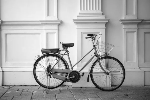 B&W rower starodawny zaparkowany obok białej ścianie. — Zdjęcie stockowe