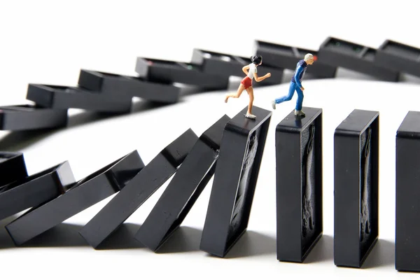 Tiny toys escape running away on dominoes are falling. — Stock Photo, Image