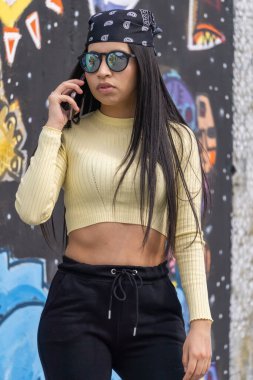 Sokakta siyah güneş gözlüklü ciddi bir kız konuşuyor.