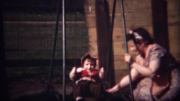 Mãe ajudando menina no parque infantil swingset — Vídeo de Stock