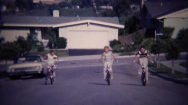 Kids riding bikes uphill on street — Stock Video