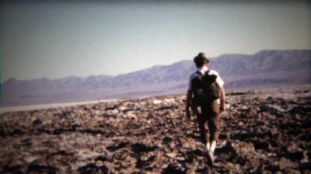 Man walking across mountainous dry lake — Stock Video