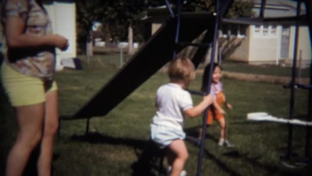 Boy and sister sliding on backyard playground — Stock Video