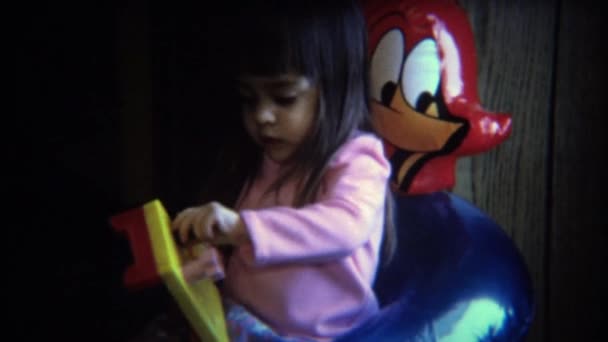 Chica resuelve rompecabezas en silla inflable woody woodpecker — Vídeo de stock