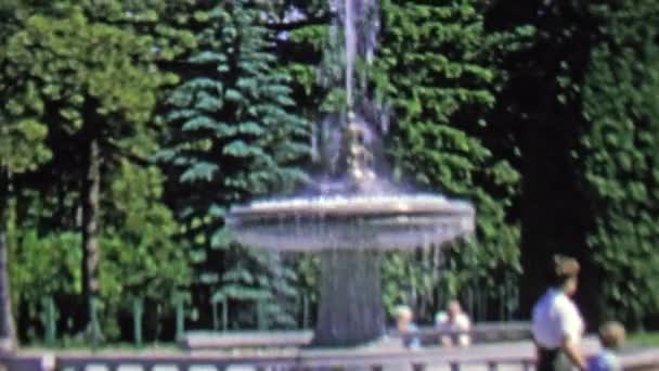 Водный фонтан в общественном парке, который посещает семья — стоковое видео