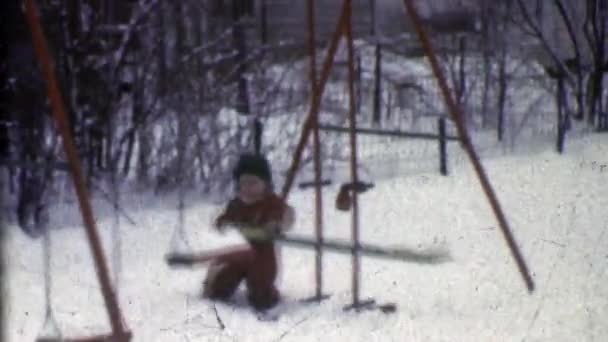 Pojke försöker spela på vintern swing set lekplats — Stockvideo