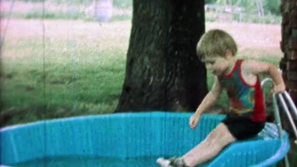 Boy goes down kiddie slide into swim pool — Stock Video