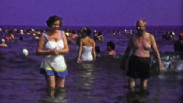 Älteres Paar spielt am überfüllten Strand — Stockvideo