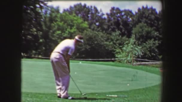 Homme puces balle de golf de gouttes dans le trou spectateur — Video