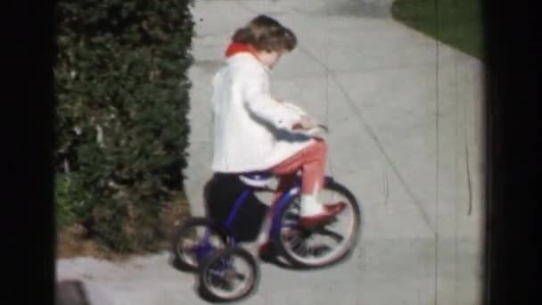 Flicka ridning trehjuling cykel på bostäder trottoar — Stockvideo