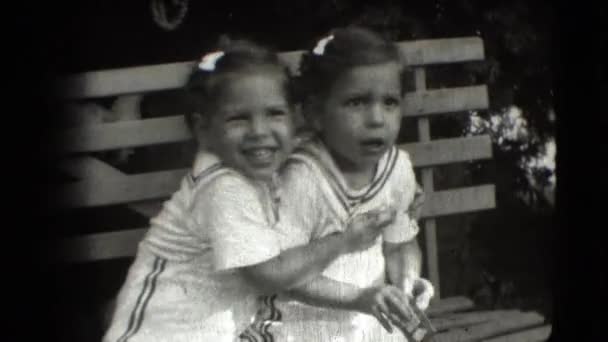 Um par de gêmeos sentados em um banco — Vídeo de Stock