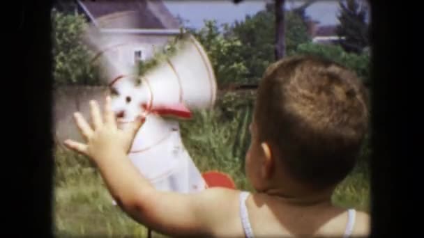 Toddler boy playing with windmill in yard — ストック動画