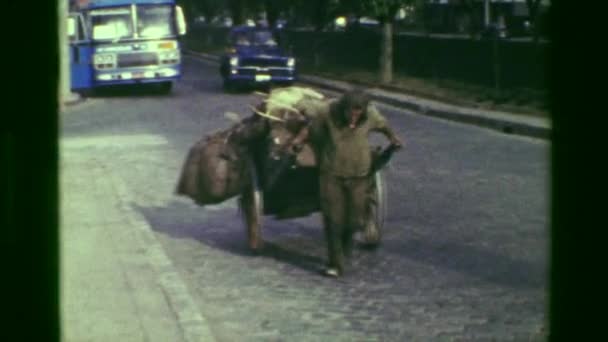 Мужчина тянет картонку с вещами на оживленной улице — стоковое видео