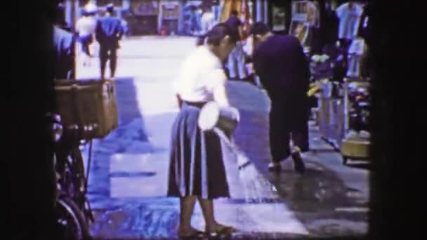 Торговец поливает тротуар, чтобы остыть и очистить проход — стоковое видео