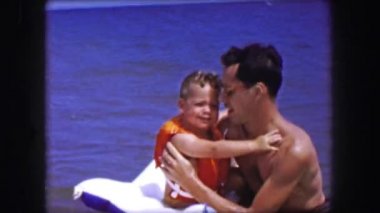 Baba yürümeye başlayan çocuk evlat şişme bota tutar.  