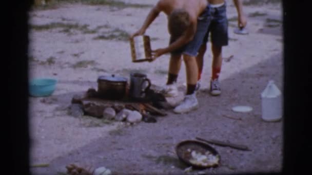 Niños cocinan sobre un fuego — Vídeo de stock