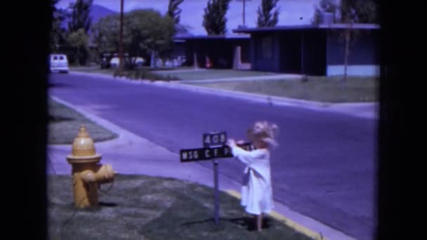 Niño haciendo giros lentos alrededor de poste con nombres de calles — Vídeo de stock