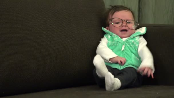 Baby sitzt auf Couch mit Brille — Stockvideo