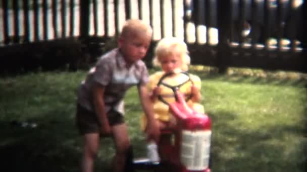 Hermano empujando hermana en juguete tractor — Vídeos de Stock