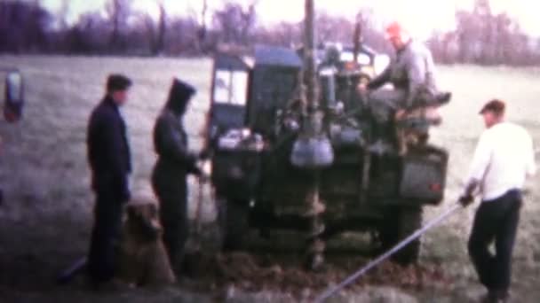 Hombres cavando agujeros de poste eléctrico con el tractor — Vídeo de stock