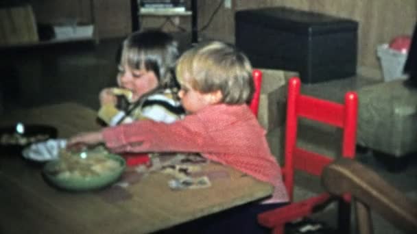 Testvérek eszik snack étel a romper-szoba ebédlőasztal — Stock videók