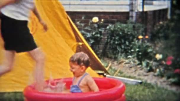 Брат шлепает малыша в детский бассейн — стоковое видео