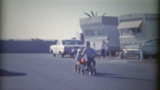 Niño en bicicleta con chica en remolque — Vídeo de stock