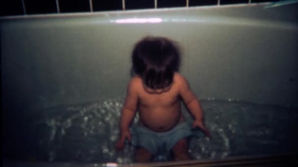 Bebê espirrando na banheira com toalha no colo — Vídeo de Stock
